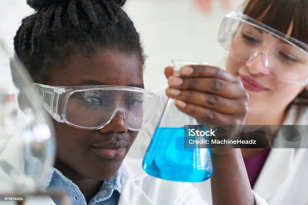 Studentessa e insegnante che conduce un esperimento di chimica - Foto stock royalty-free di Scienza