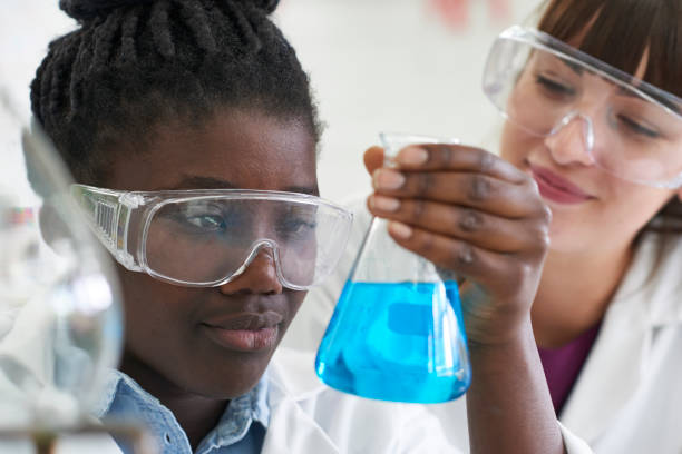 female pupil and teacher conducting chemistry experiment - physics classroom teaching professor imagens e fotografias de stock