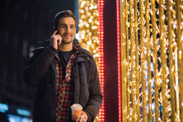 istock Man talking on the smart phone beside Christmas lights 875586434