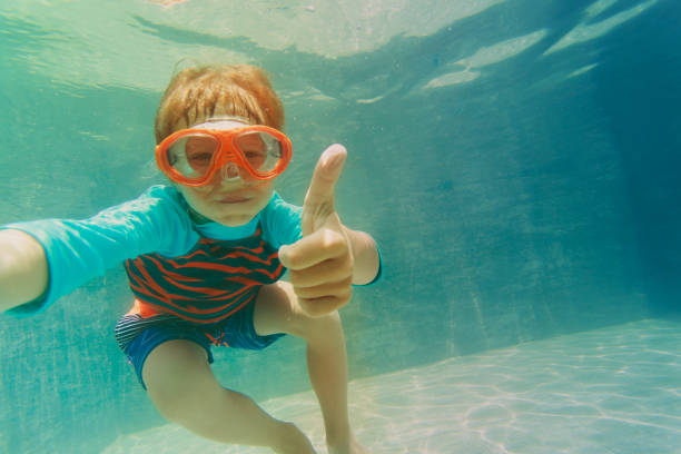istock happy boy swimming underwater with thumbs up 875593078