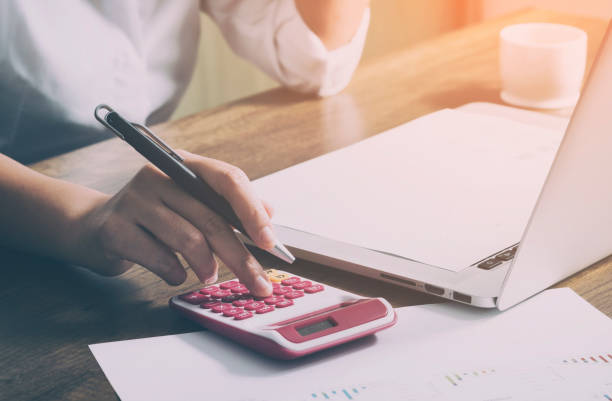 istock Young female calculates cost on desk at home office 875593190