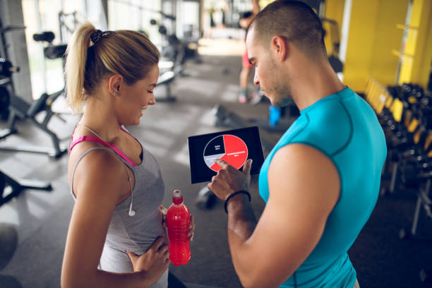 istock Trainer explaining workout regime to young sporty woman 875596560