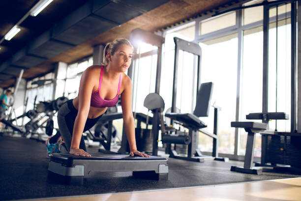istock Athletic women doing push-ups on step aerobics at a gym. 875598908