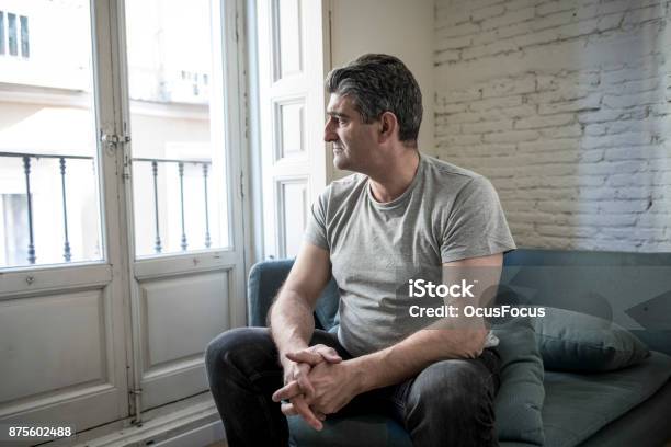 Photo libre de droit de Homme Triste Et Inquiet 40 Ans Ou 50 Ans Avec Des Cheveux Gris Assis À La Maison Canapé Regardant Déprimé Et Le Gaspillage Dans Lexpression De Visage De Tristesse Dans Le Concept De Problèmes De Dépression Et De La Vie banque d'images et plus d'images libres de droit de Hommes