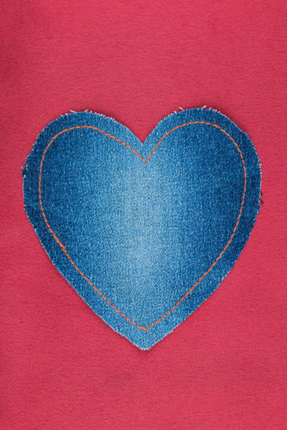 istock Heart made of denim lies on a red satin. Space for text. 875618992