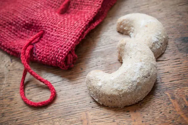 Photo of cookies in the shape of a crescent moon with red christmas sock decoration  on wooden background