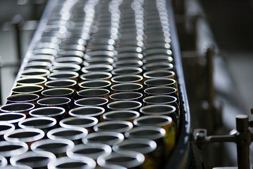 Filling of colorful beverage cans on production line.