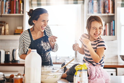 Shot of a little girl having fun while baking with her mother in the kitchen