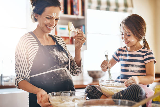 Baking is a team effort that they love to share Shot of a little girl having fun while baking with her mother in the kitchen flour mess stock pictures, royalty-free photos & images