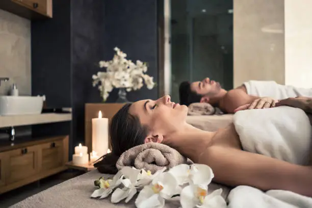 Photo of Man and woman lying down on massage beds at Asian wellness center