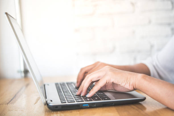 istock woman hand using laptop on vintage wooden table in cafe. 875644046