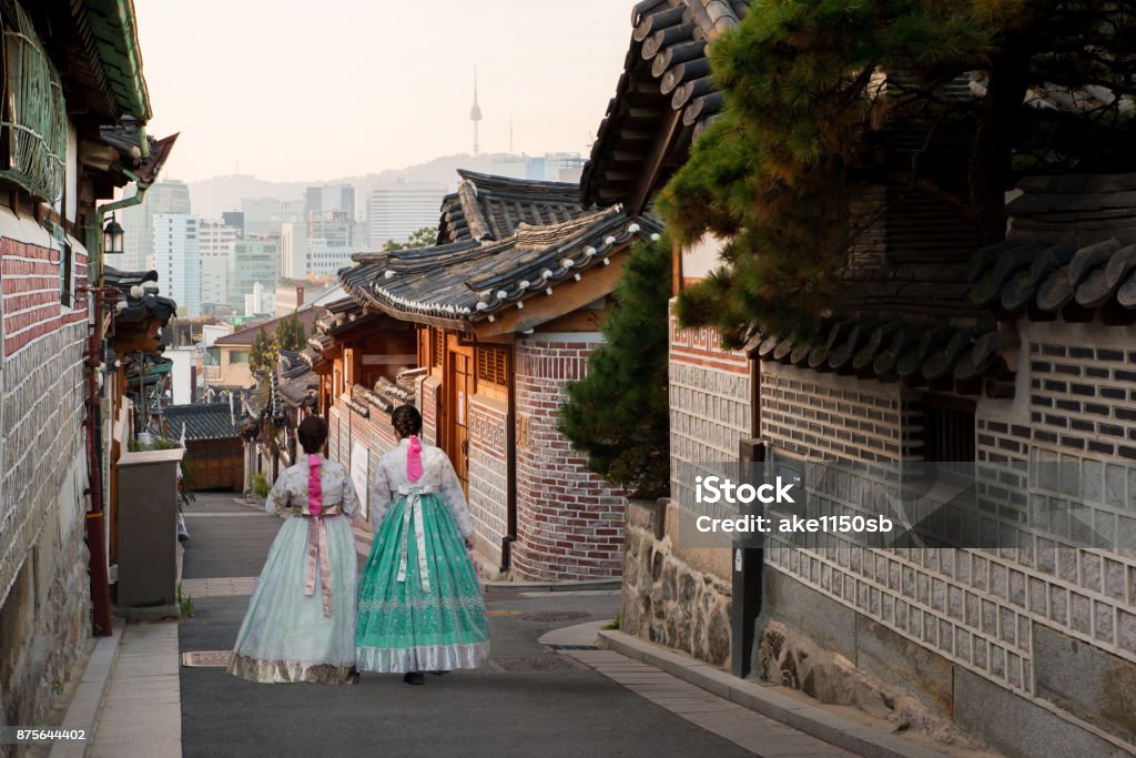Detrás de dos mujeres vestidas de hanbok caminando por las casas de estilo tradicional de Bukchon Hanok Village en Seúl, Corea del sur. - Foto de stock de Corea libre de derechos