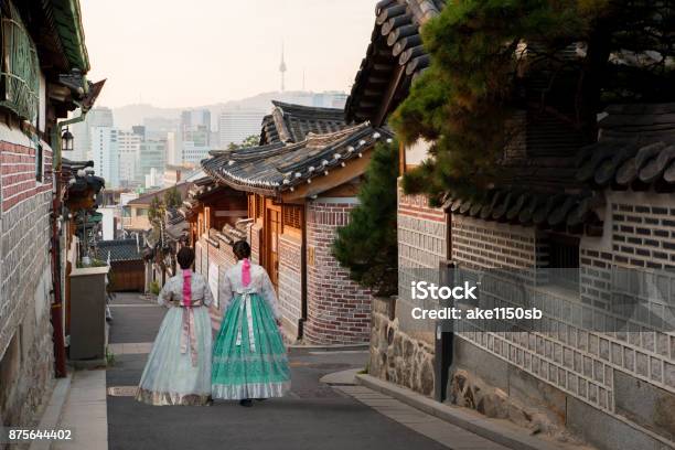 Detrás De Dos Mujeres Vestidas De Hanbok Caminando Por Las Casas De Estilo Tradicional De Bukchon Hanok Village En Seúl Corea Del Sur Foto de stock y más banco de imágenes de Corea