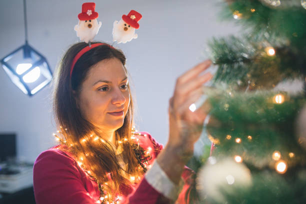 istock Happy young woman decorating christmas tree at home 875647946