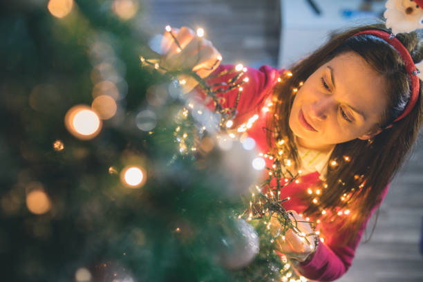 heureuse jeune femme décoration arbre de noël à la maison - christmas ball christmas ornament human hand photos et images de collection