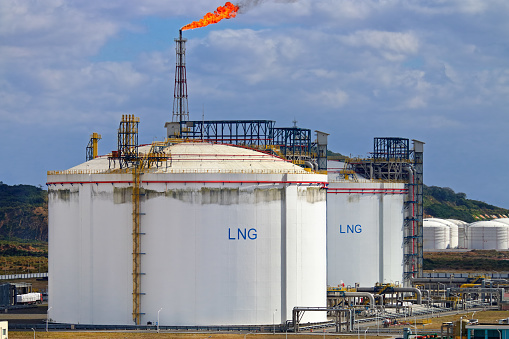 Picture of large LNG (Liquefied natural gas) tanks at LNG regasification terminal, with gas flare stack