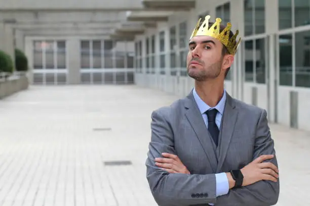 Arrogant businessman with a crown in office space.