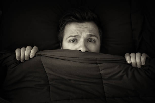 istock Caucasian young man hiding in bed under the blanket at home. 875652142