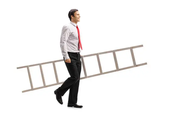 Full length profile shot of a formally dressed man holding a ladder and walking isolated on white background