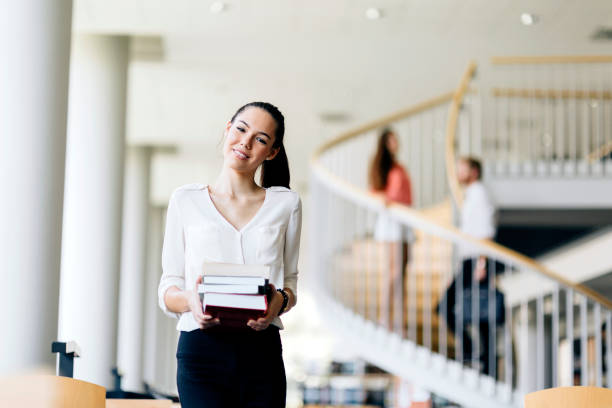 istock Beautiful woman holding books in a library 875654976