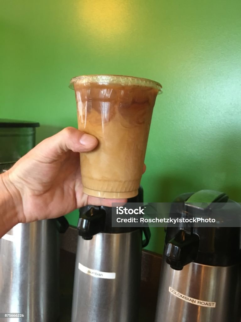 Holding my ice coffee as my daily routine Holding up my ice coffee my daily routine. Male hand holding up ice coffee drink with green background wall 20-24 Years Stock Photo