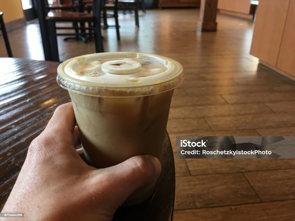 Holding my ice coffee on a coffee table as my daily routine Holding up my ice coffee my daily routine. Male hand holding up ice coffee drink on a coffee table 20-24 Years Stock Photo