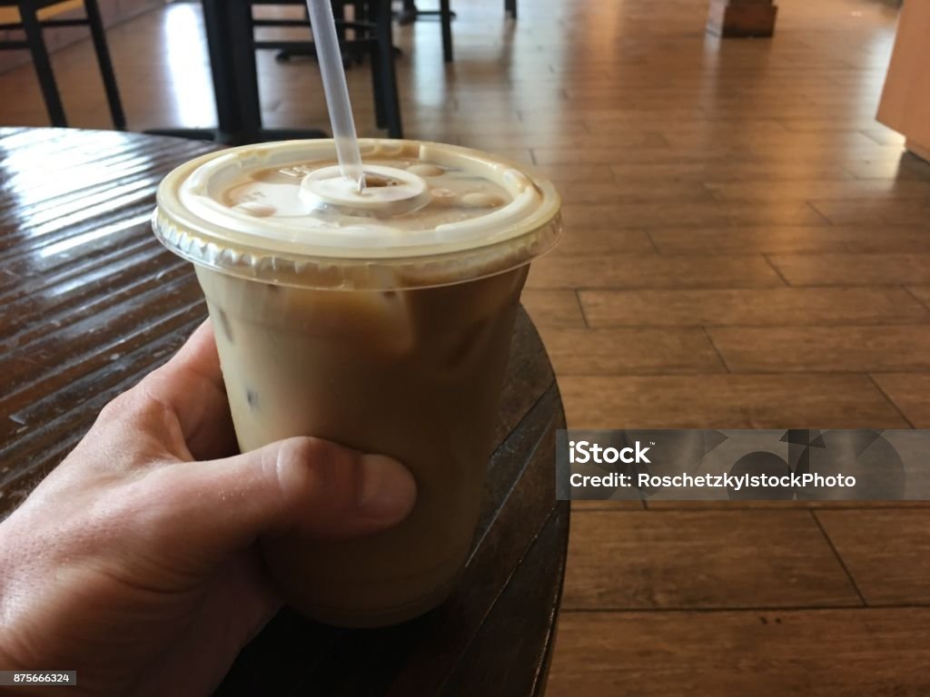 Holding my ice coffee on a coffee table as my daily routine Holding up my ice coffee my daily routine. Male hand holding up ice coffee drink on a coffee table 20-24 Years Stock Photo