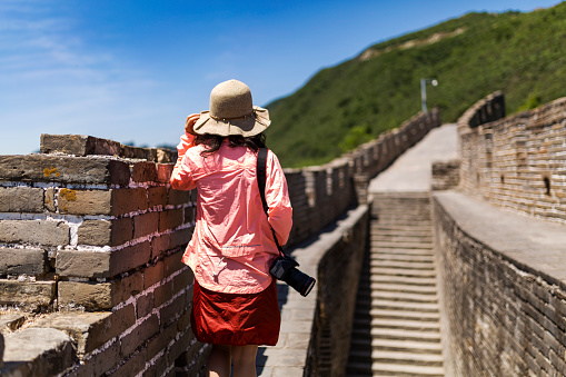 The young woman With Camera Standing At Great Wall Of China.