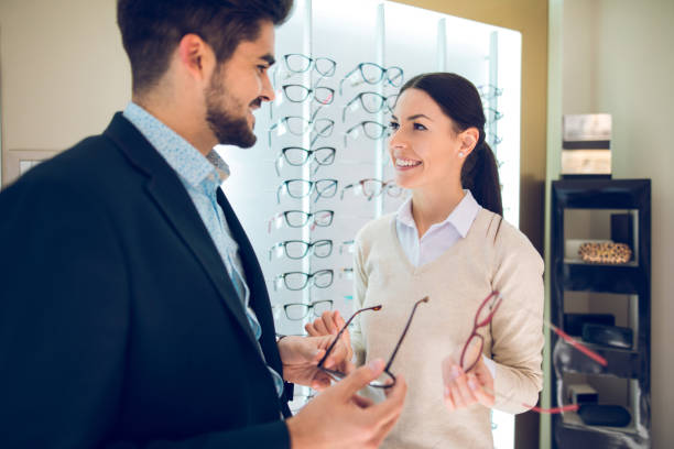 istock Smiling couple selecting eyeglasses in optical store 875669554