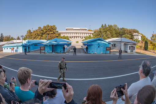 A tour group take photos at the Joint Security Area (JSA) conference buildings between South and North Korea in the Demilitarised Zone (DMZ). Technically an active war zone, the huts are now used for diplomatic meetings.