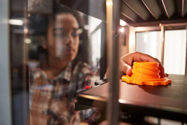 Photo of Female College Student Printing 3D Object In Design Lesson