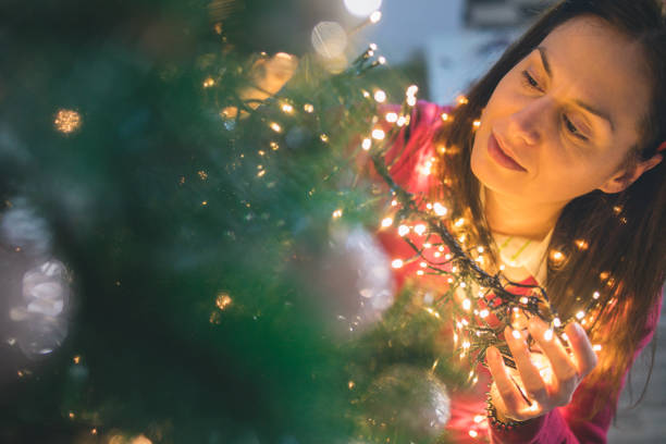 istock Happy young woman decorating christmas tree at home 875673612