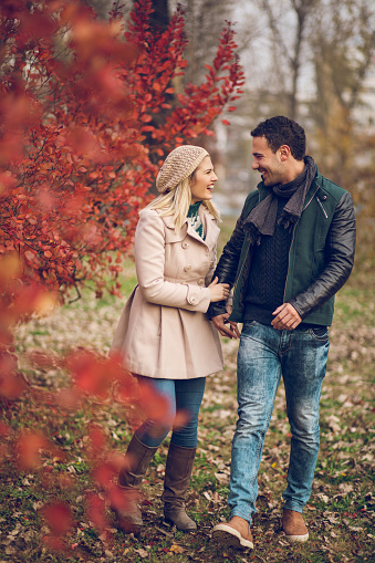 Young embraced couple taking a walk in autumn park. Copy space.