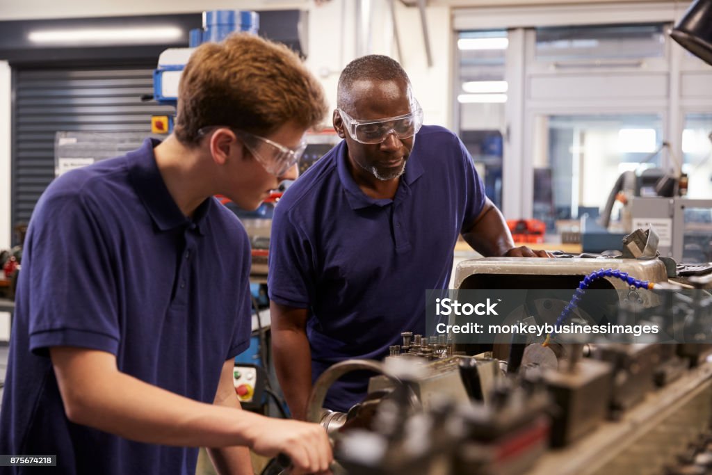 Engineer Showing Teenage Apprentice How To Use Lathe Manufacturing Stock Photo