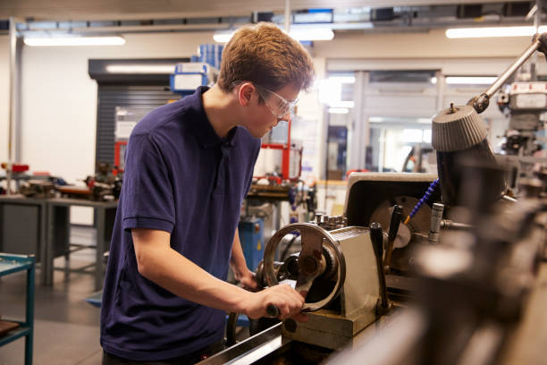 istock Male Teenage Apprentice In Engineering Factory Using Lathe 875674222