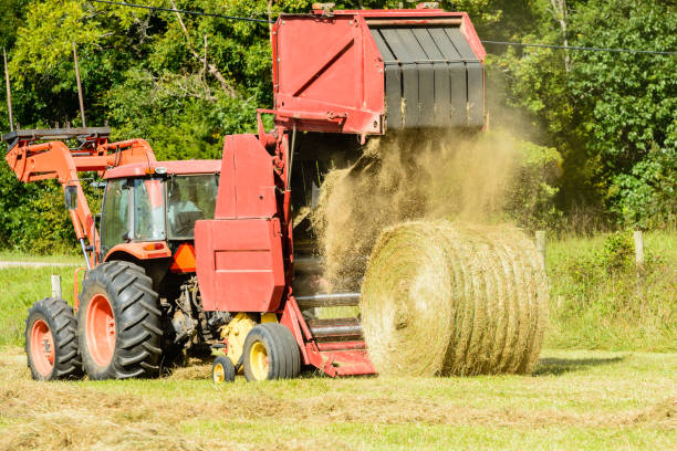 Hay baler dumping a bale of hay A hay baler dumps a newly formed round bale of hay. hay baler stock pictures, royalty-free photos & images