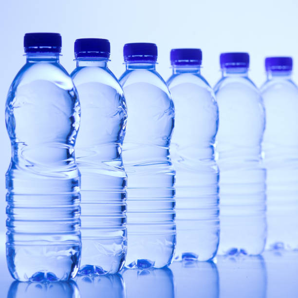garrafas de plástico de água isolado em fundo azul - water bottle purified water water drink - fotografias e filmes do acervo