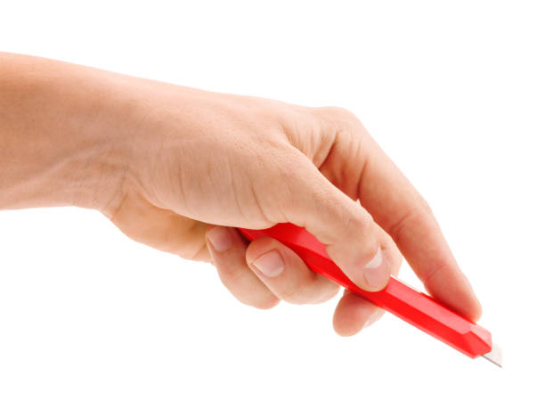 Red stationery knife in hand isolated on white background