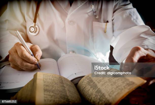 Doctor Writes On A Book Of Ancient Medicine Conceptual Image Stock Photo - Download Image Now