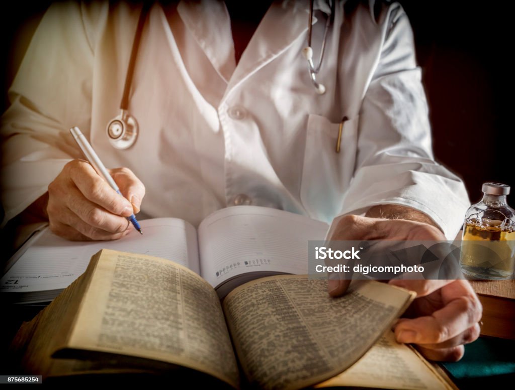 Doctor writes on a book of ancient medicine, conceptual image Adult Stock Photo