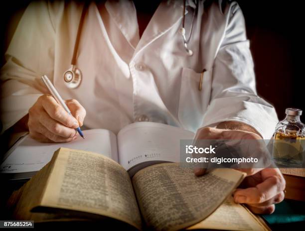 Doctor Writes On A Book Of Ancient Medicine Conceptual Image Stock Photo - Download Image Now