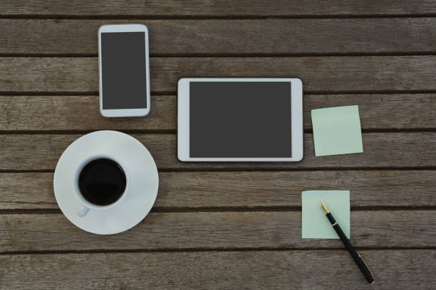 istock Electronic gadgets, black coffee, pen and sticky note on wooden plank 875689620