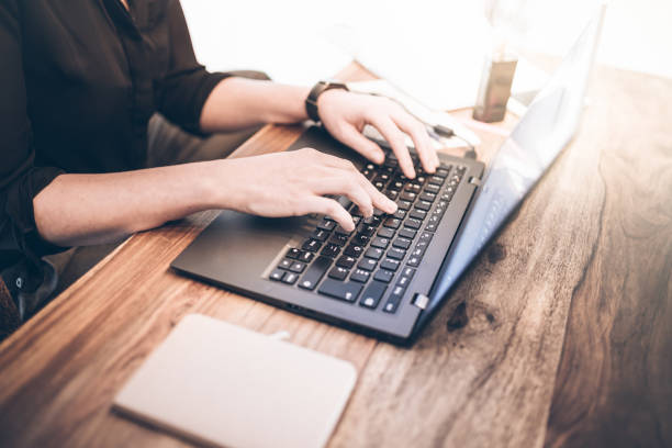 istock young woman sitting at rustic wooden table working with notebook computer 875690398