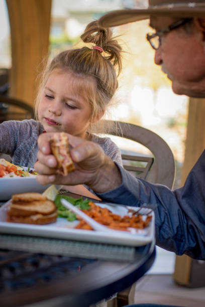 istock Grandpa and Granddaugher Eating Lunch 875693312