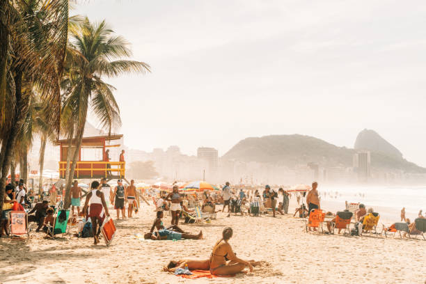 people relaxing and sunbathing at famous Copacabana beach, Rio de Janeiro, Brazil people relaxing and sunbathing at famous Copacabana beach, Rio de Janeiro, Brazil copacabana rio de janeiro photos stock pictures, royalty-free photos & images