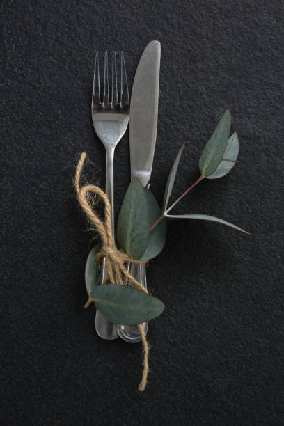 istock Fork, butter knife tied up with leaf on black background 875715096