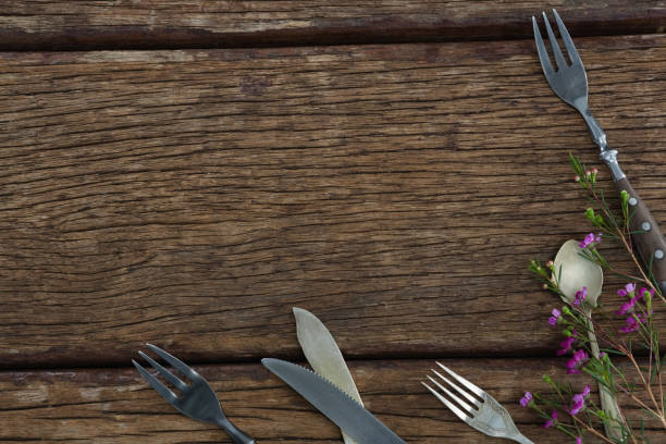 istock Fork, butter knife and spoon with flower on wooden table 875715142