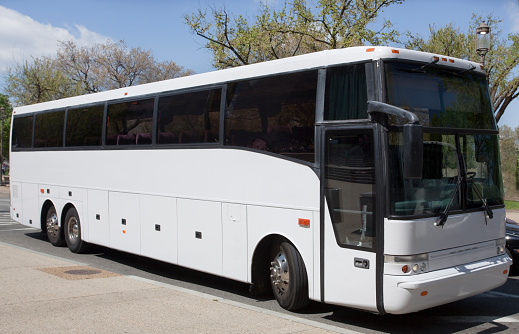 Parked white tour charter sightseeing bus in urban location. Horizontal.