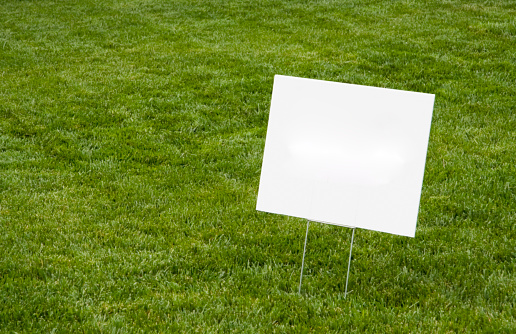 Blank white sign on newly cut grass. Copy space. Horizontal.