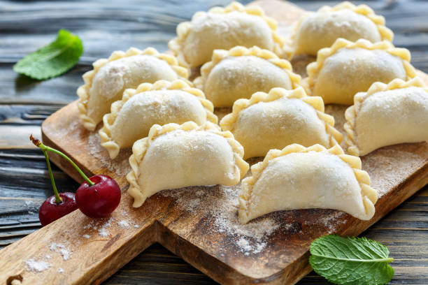 Homemade dumplings with cherries. Homemade dumplings with cherries on the board, floured, selective focus. pierogi stock pictures, royalty-free photos & images